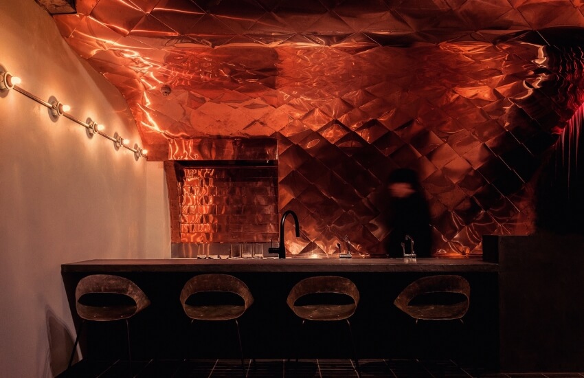 Interior of Poppy Lounge with copper-tiled ceiling and long wooden table